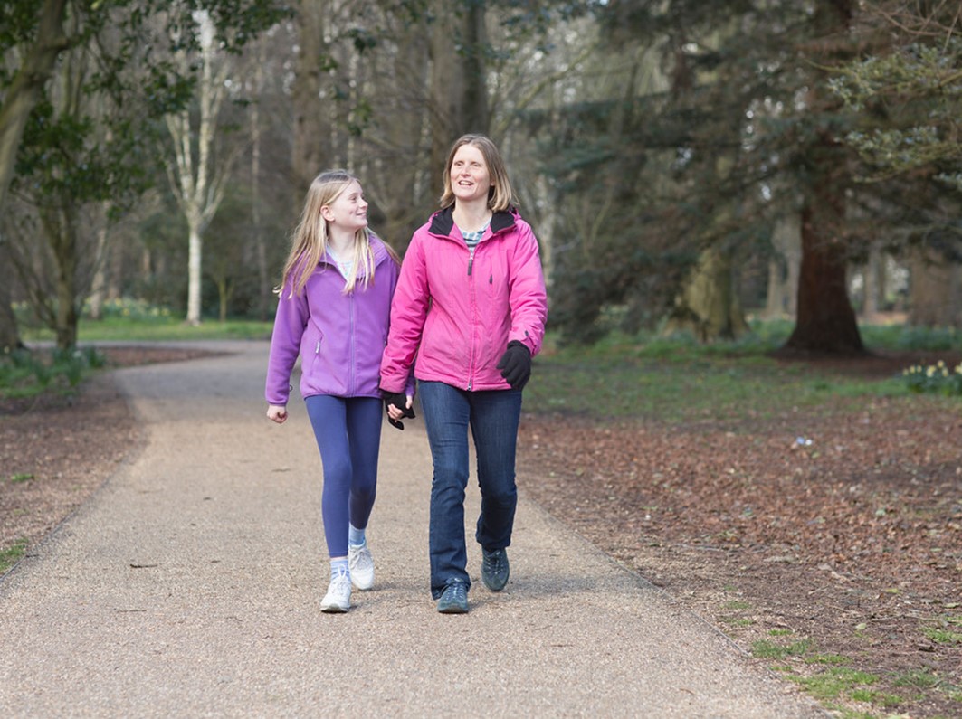 A woman and a teenage girl walking through a park